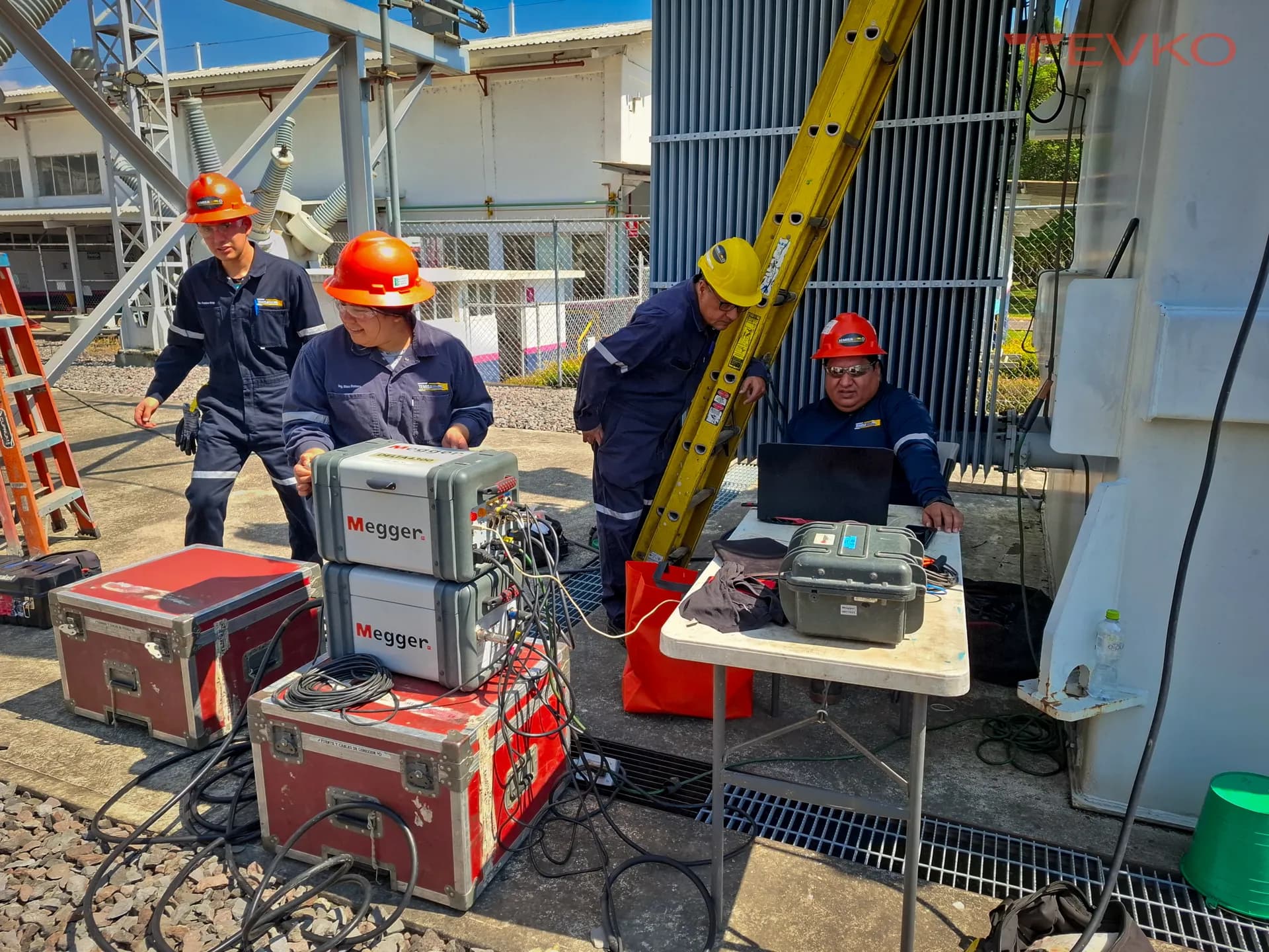 Cuadrilla con dos instrumentos Megger conectados, estuches de transporte y computadora portátil, durante pruebas eléctricas en una subestación